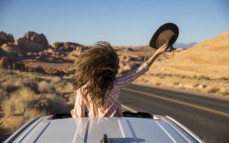 A woman celebrating out her sunroof window in the desert.